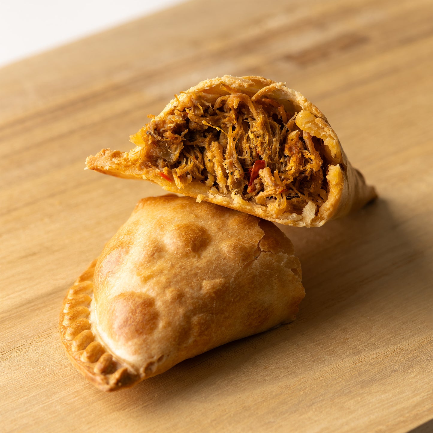 Empanada argentina rellena de carne mechada — masa crujiente con jugosa carne deshebrada y sazonada al estilo tradicional, ideal para fiestas y reuniones, disponible en RockaPan con envío a todo EE. UU.”