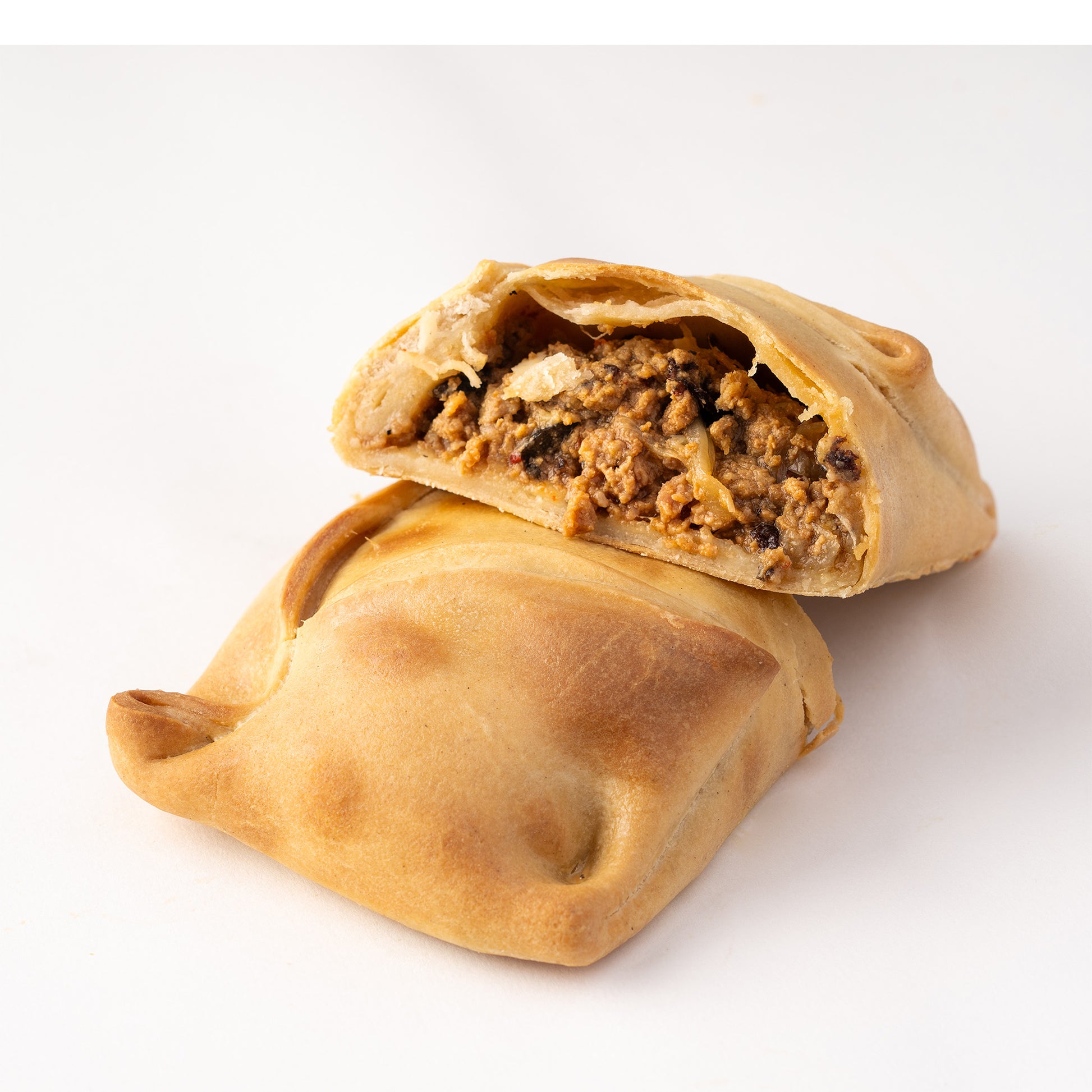 Imagen de empanada chilena rellena de carne molida, cebolla y condimentos típicos, horneada con masa dorada y crujiente.